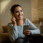 happy-woman-listening-music-earphones-while-using-mobile-phone-home_637285-4461